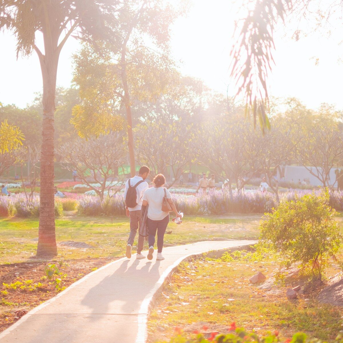 two people walking down a path in a park