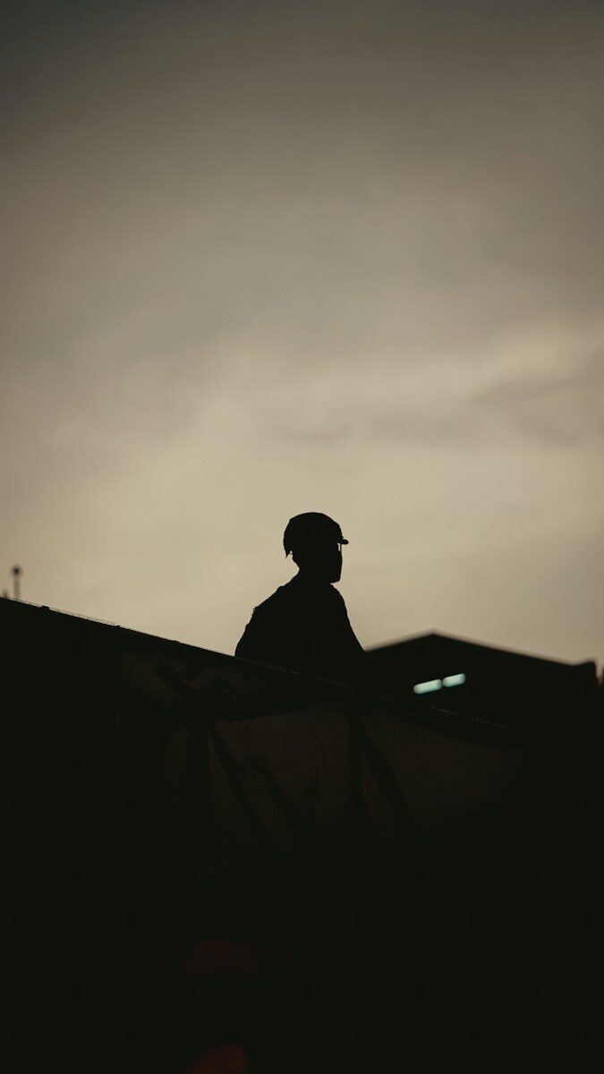 Silhouette of a person wearing a hard hat at dusk