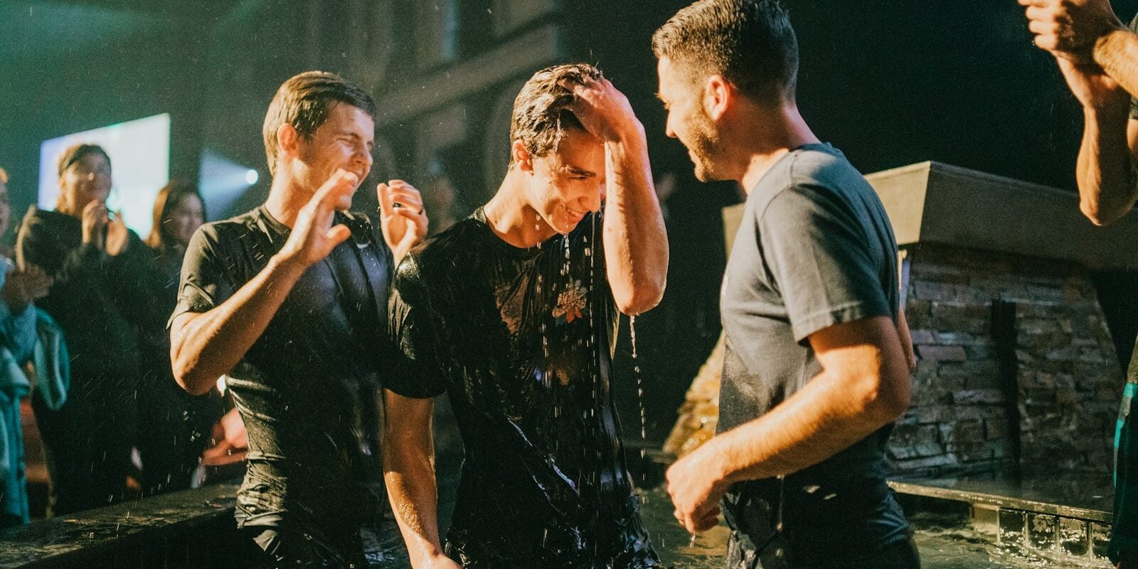three men standing on black tub full of water