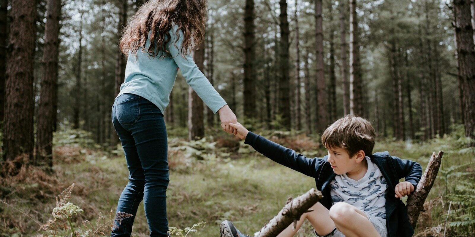 boy and girl playing on three tree log