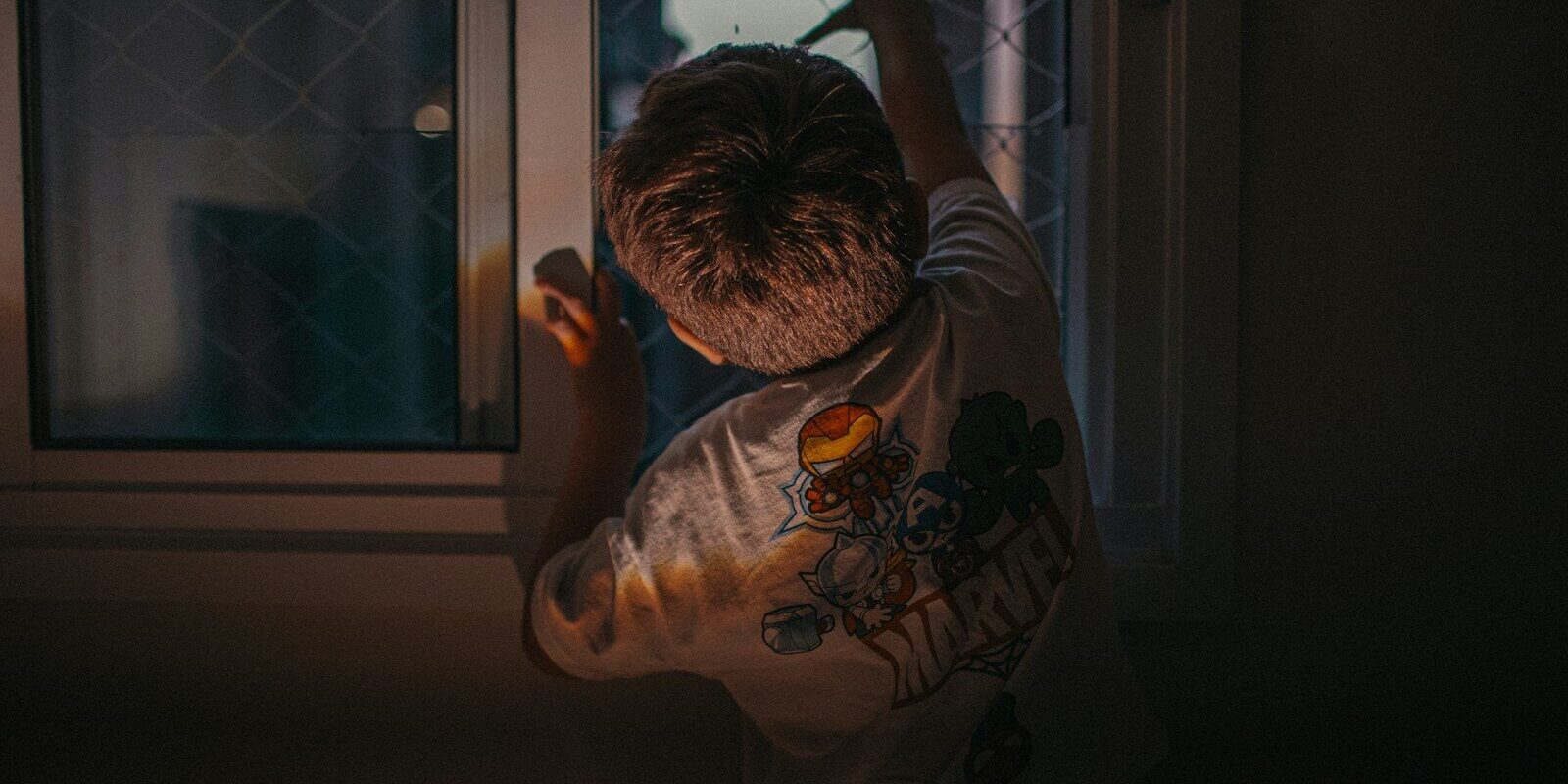 Young boy looking out a window at night